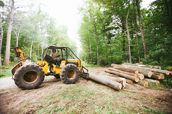 A man driving a tractor at a wood harvesting mill.