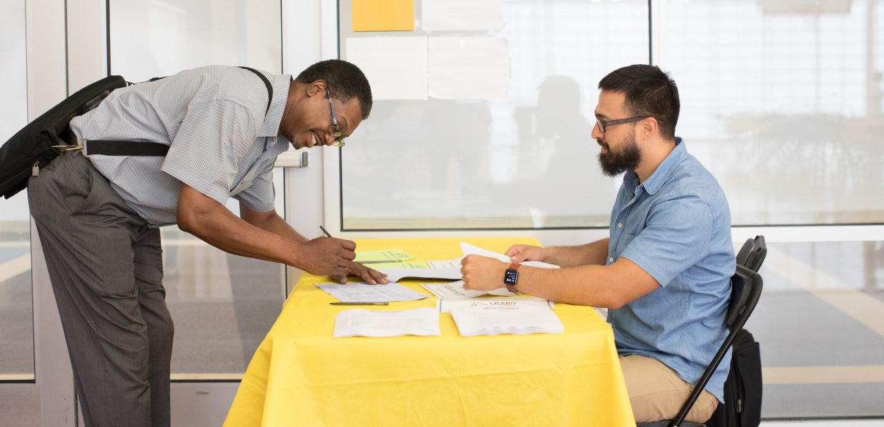 A man signing in to attend a community meeting.