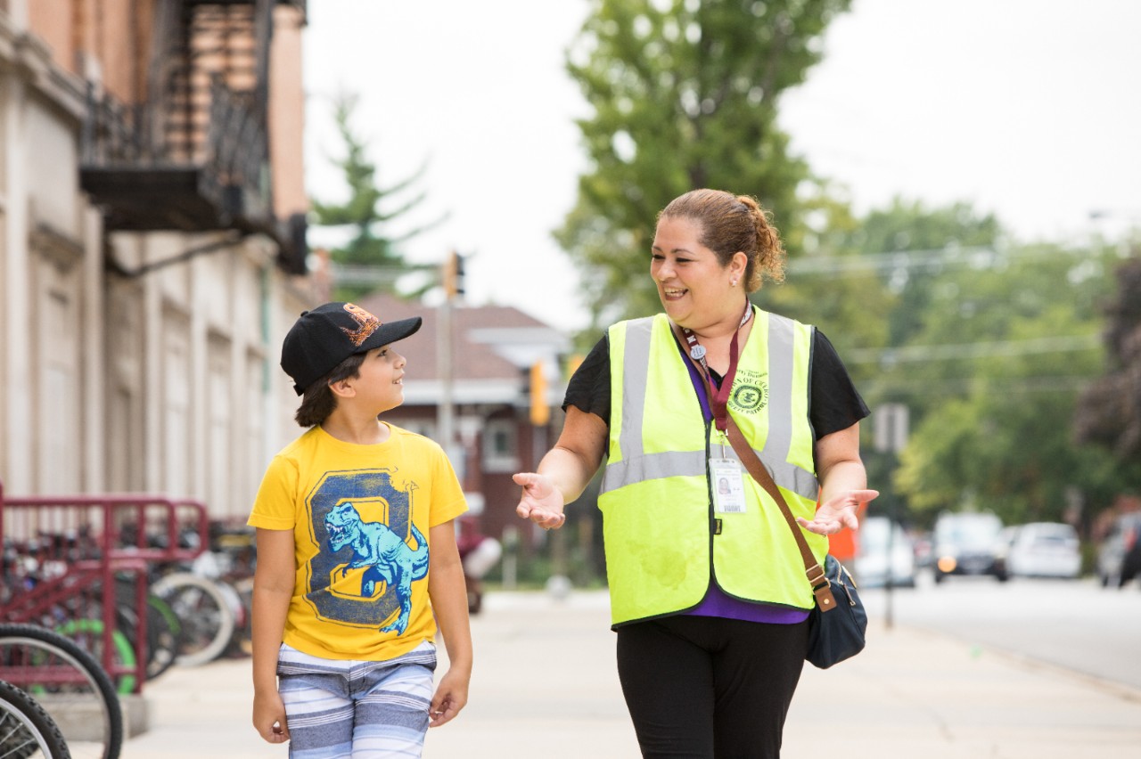 A crossing guard and student walking together.