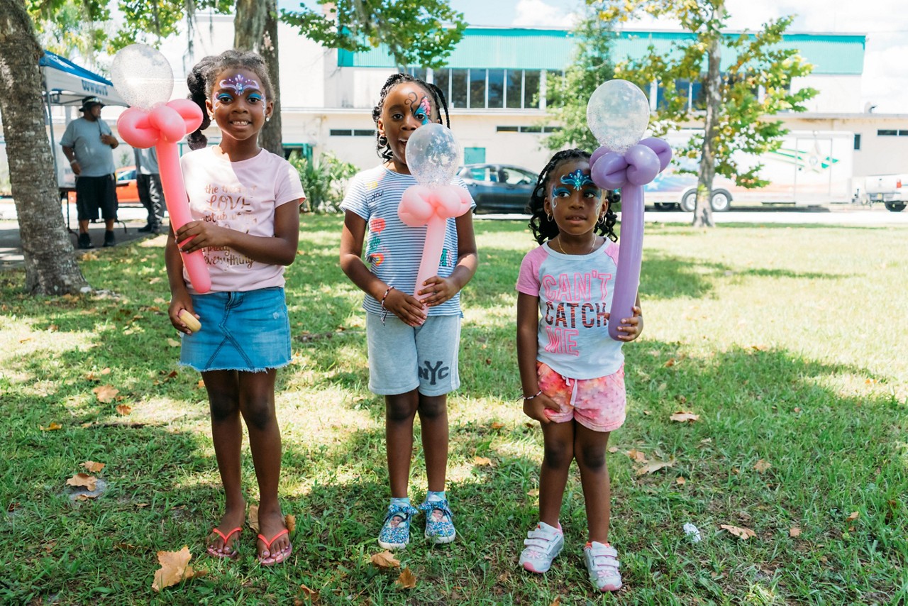 Three young girls enjoyng a community event with balloon animals.