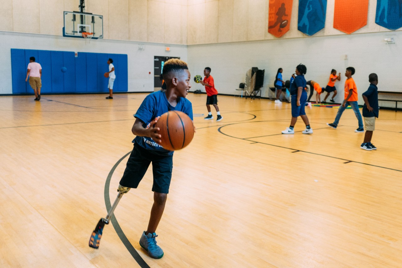 Hungerford Elementary School student, Jayden, enjoys a game of basketball with his peers at the Boys & Girls Club after school.