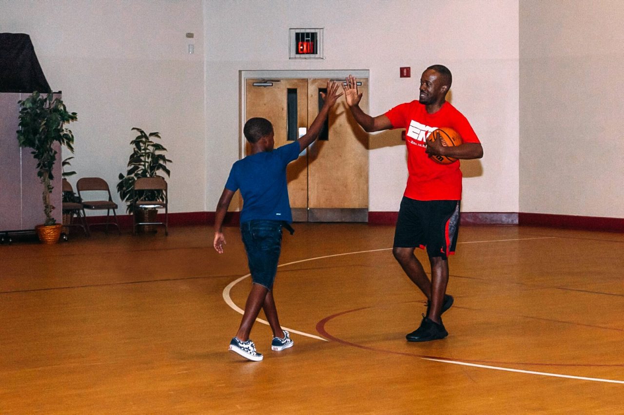 A man and boy high-five while playing basketball.