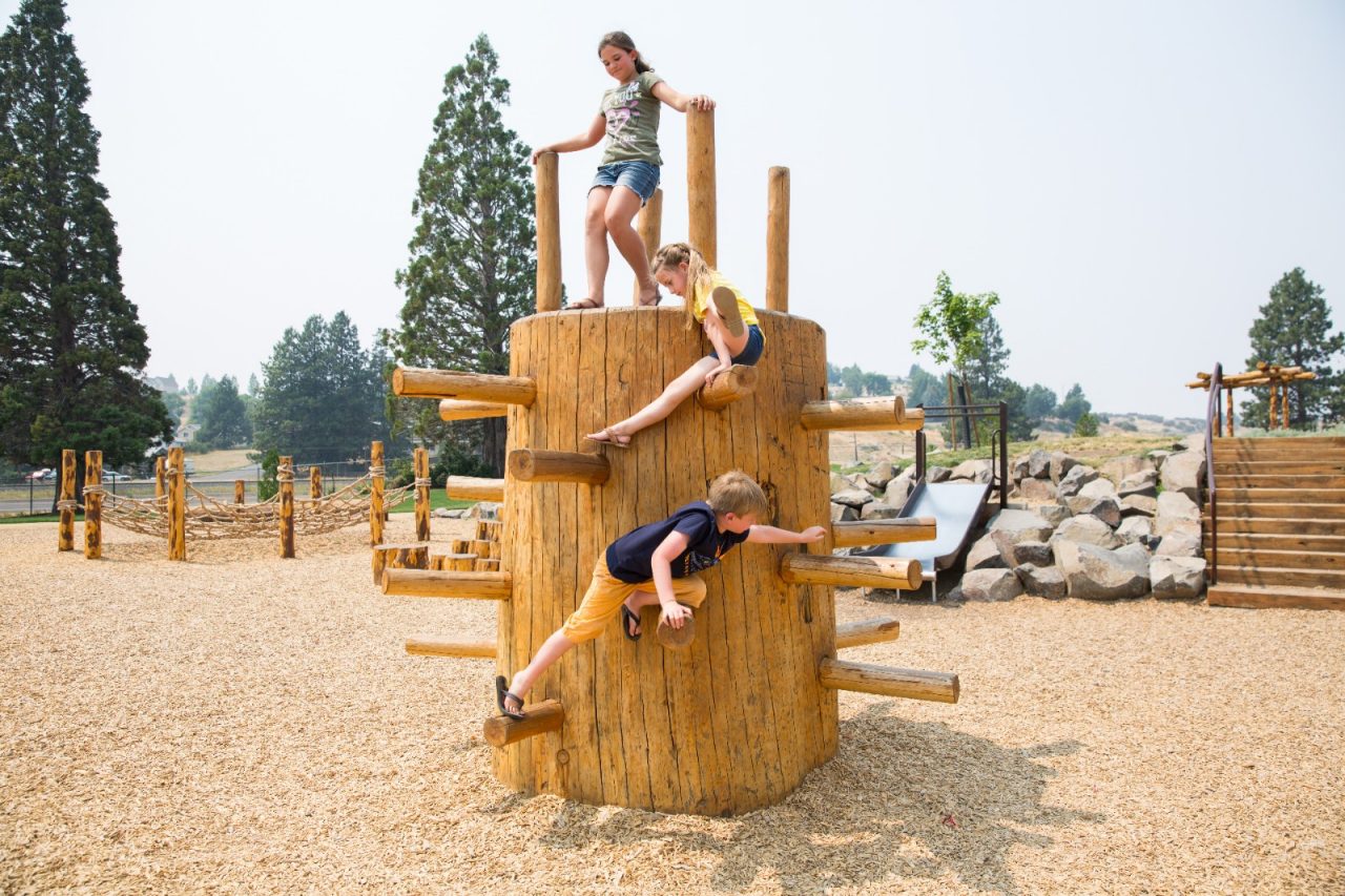 Children playing on a park's wooden playground equipment.