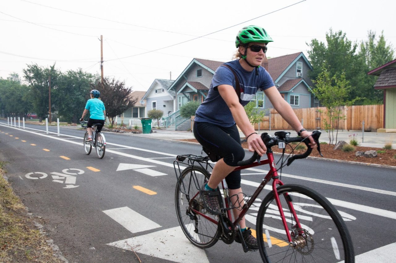 Jennifer Little wearing a helmet while riding a bike in a bike lane.