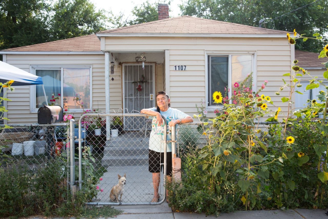 An woman and her dog standing in her fenced yard.