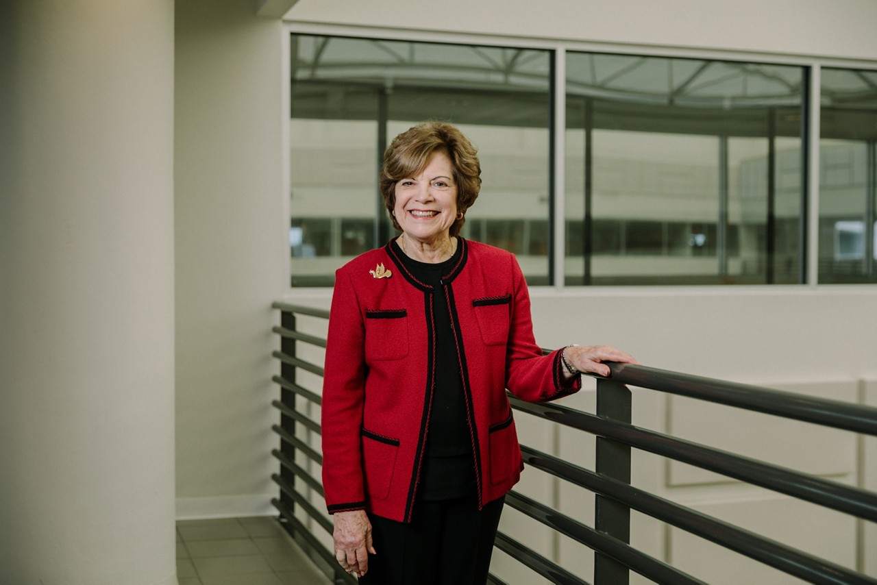 A smiling woman standing in an office hallway.