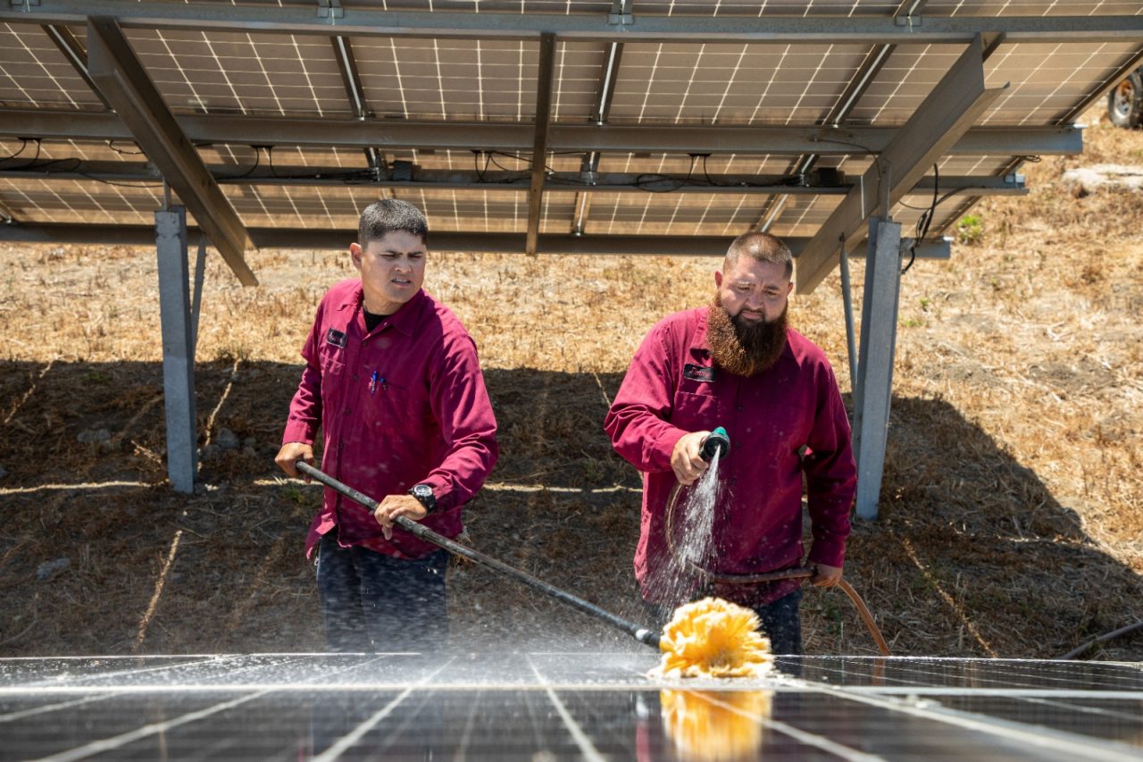 City employees Andrew Lujan (left) and Jamie Vasquez wash solar panels.