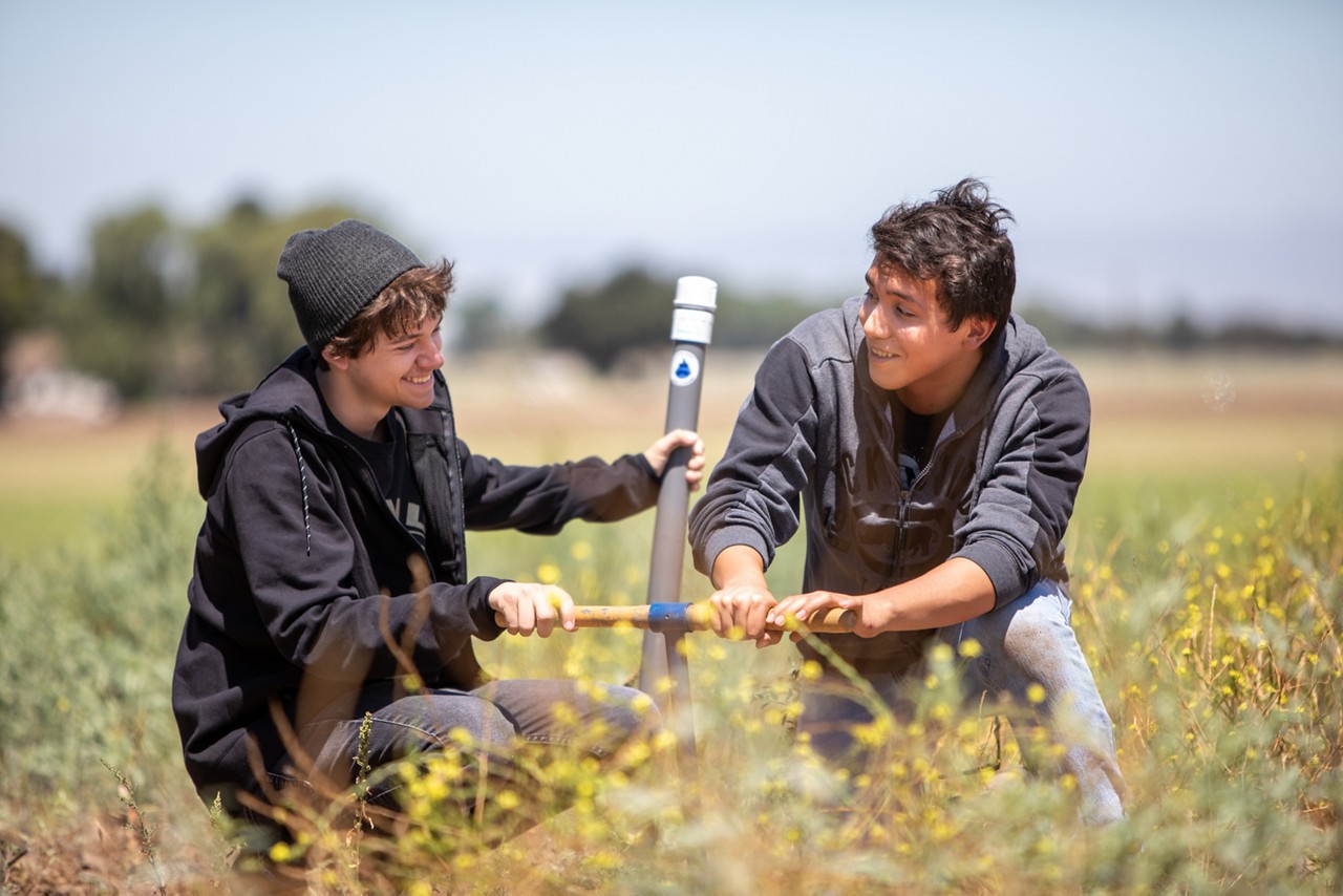 Jerome Russell (left) and Pablo Mendoza-Contreras install a water monitor in a field outside Gonzales.