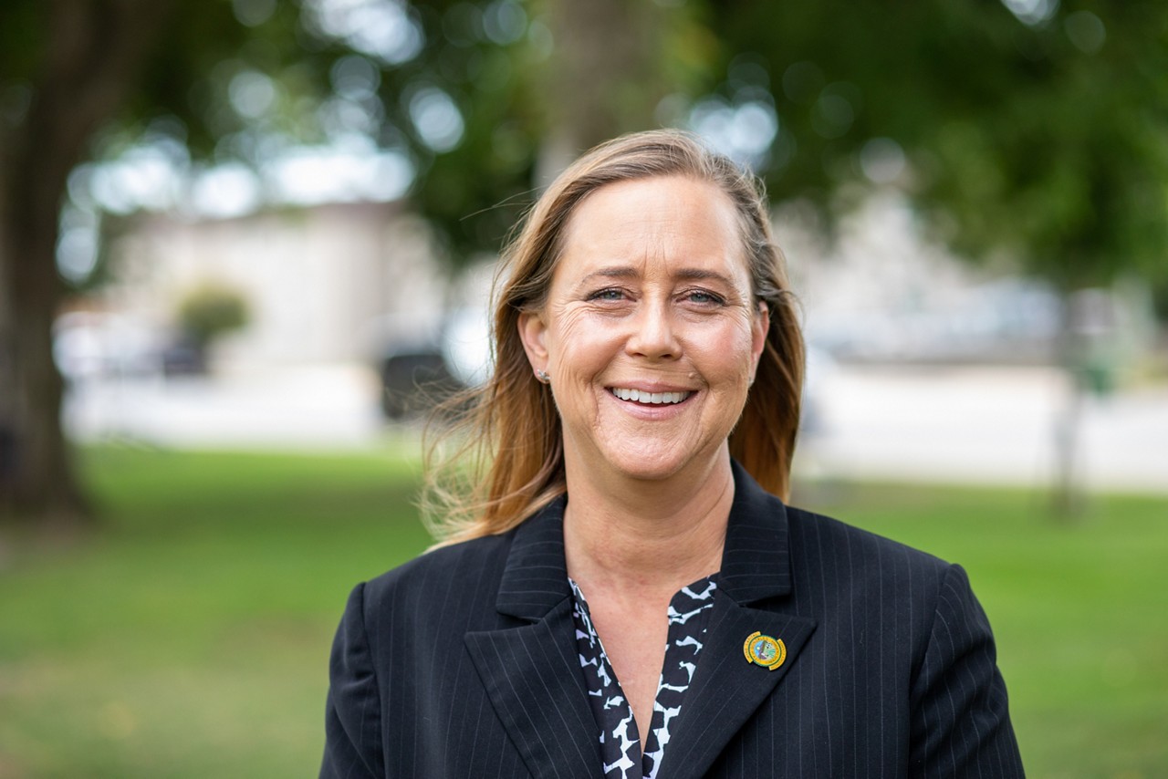 A woman in a blue blazer smiling for a photo.