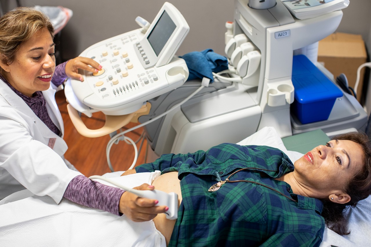 RWJF Culture of Health Prize 2019 - Gonzales, CA.  Luz Garcia (white lab coast) giving a sonogram to Barajas Quintana Rebecca (green and blue flannel). Luz Garcia received a  city-backed low interest business loan to start walk-in sonogram clinic, which is located in Gonzales pharmacy.