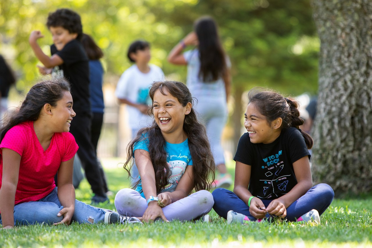 Three girls sitting in a park.