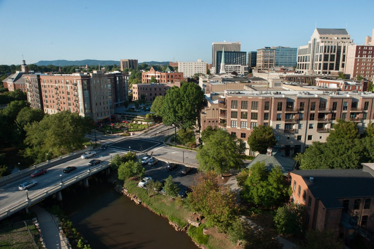 An aerial view of a downtown environment with a river running beneath a bridge.