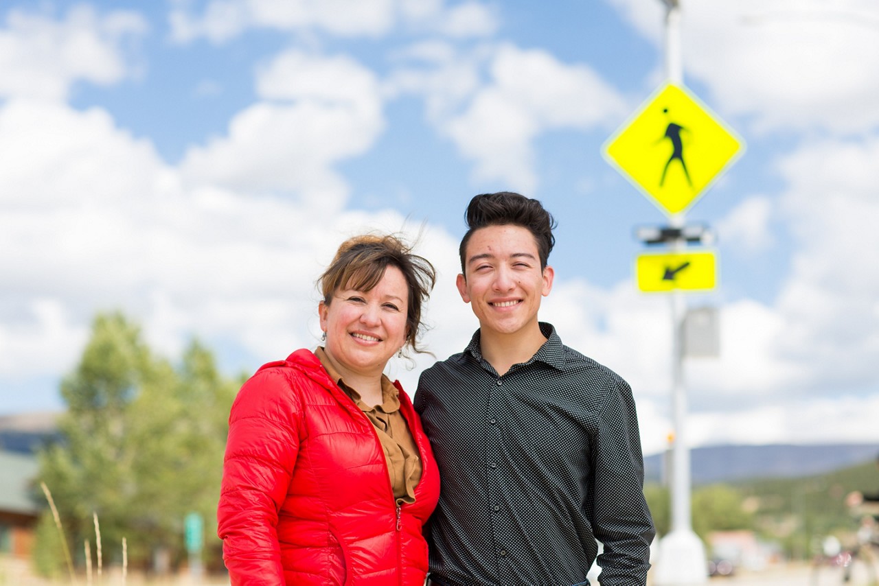 A mother and son standing in a pedestrian crosswalk.