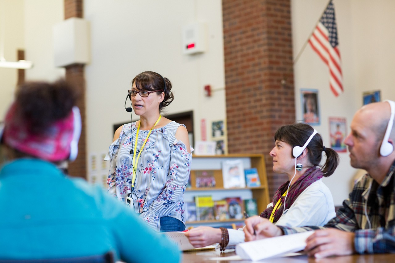 An interpreter attending a meeting of English and Spanish speakers.