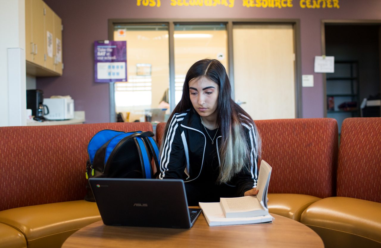 A high school student working on a laptop in a resource center.