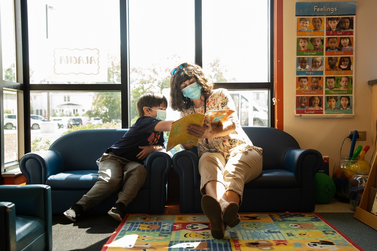 A teacher and young student reading together.