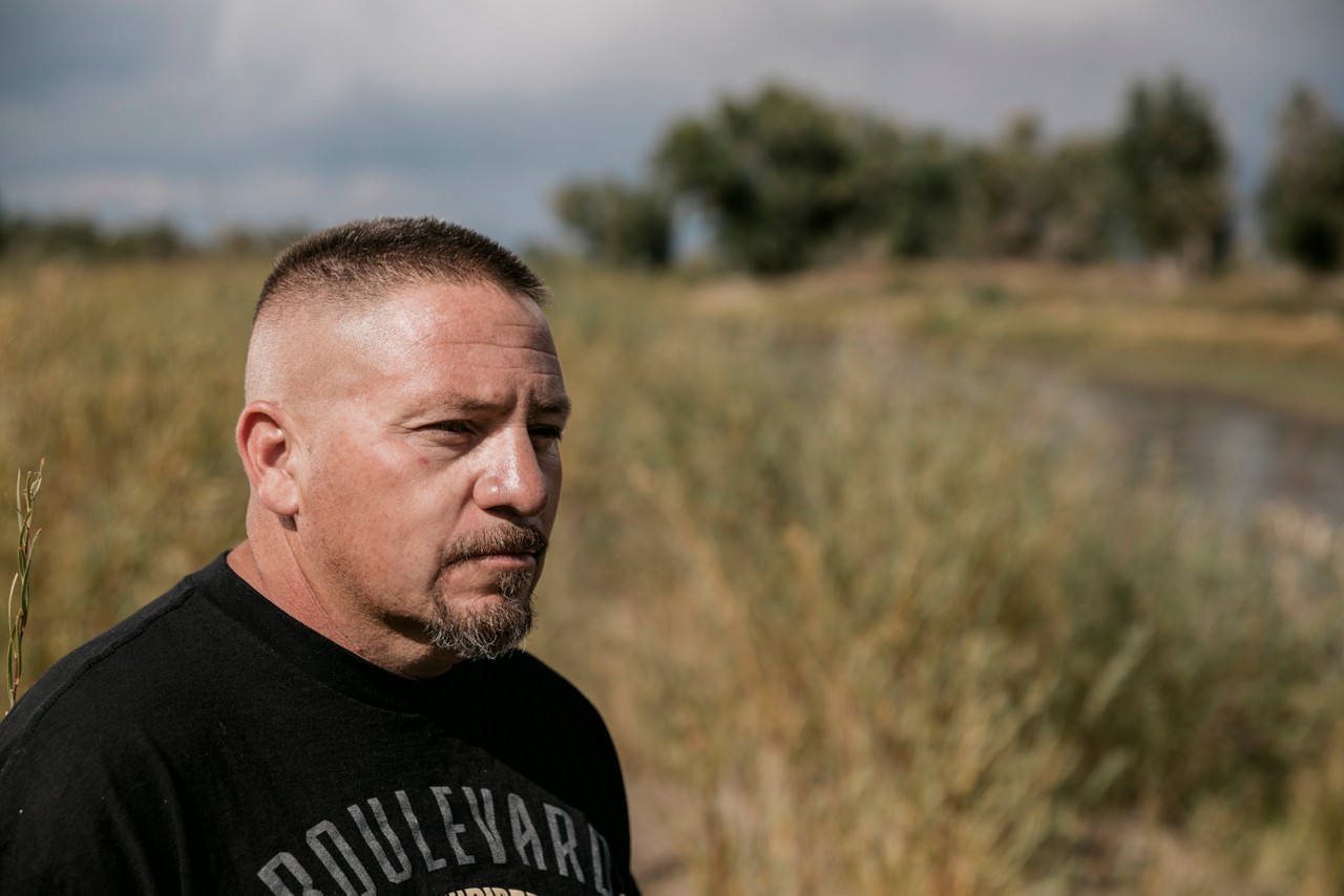 A man in a black t-shirt standing in a grassy field.