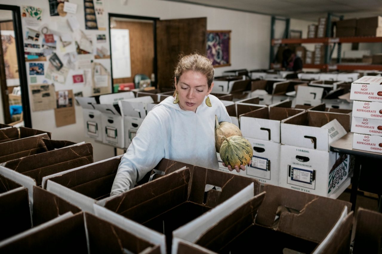 A woman sorts vegetables in cardboard boxes in a food pantry.