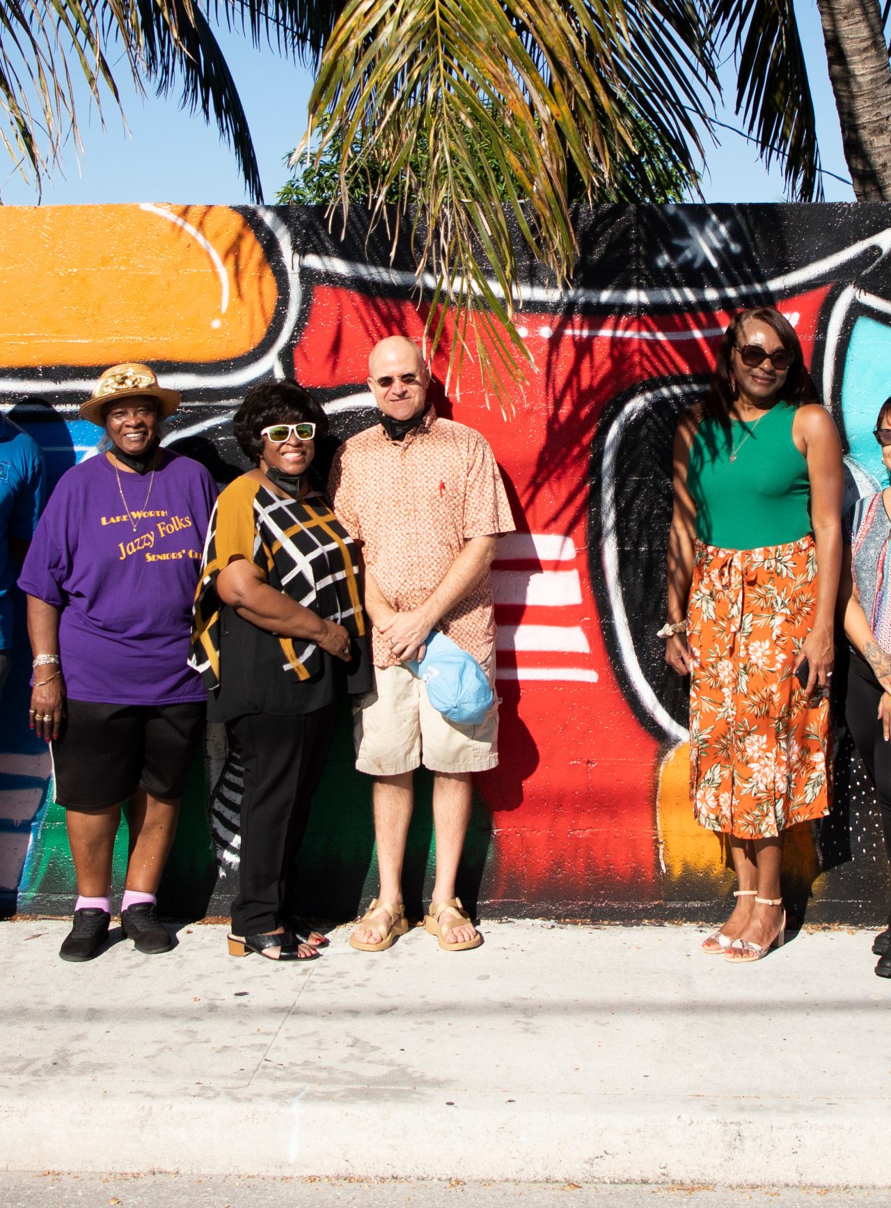 Pictured right to left as follows : Sandra Lula Gover, Roselyn Davis (brown shirt), Sidney Rodriguez, Carmelle Marcelin-Chapman (green top), Samuel Goodstein (bald man), Carla Blockson (sunglasses with black, white and brown top), Retha Lowe (purple shirt), Patrick Livingston (blue shirt) and Adella Bell (very left of frame) at the Unity Wall. A wall that formerly served as a symbol of division is now a beacon of light for inclusion and diversity in Lake Worth Beach. The wall served as an unofficial border between the residents of the "Osborne Colored Addition" and their white neighbors. The city's zoning code required Black residents to live in the Osborne subdivision until 1969. 67 South Florida professional artists and residents helped paint the 1,175 foot long wall with art murals that represent the past, present, and future of the community.