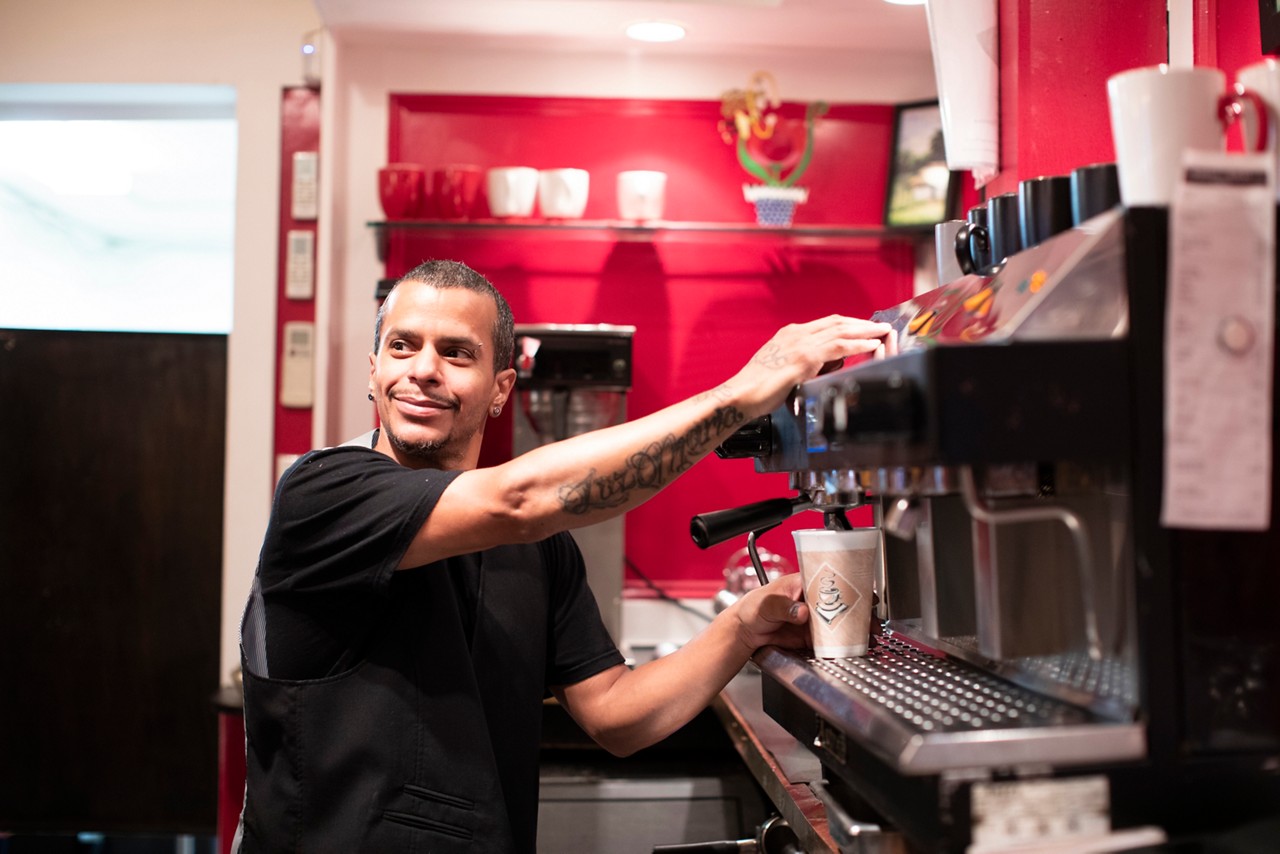 A smiling barista fills a cup with coffee.