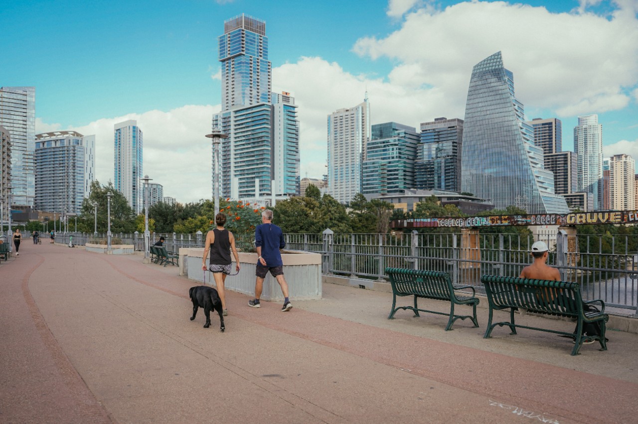 A woman and man with a dog walk along a bridge. 