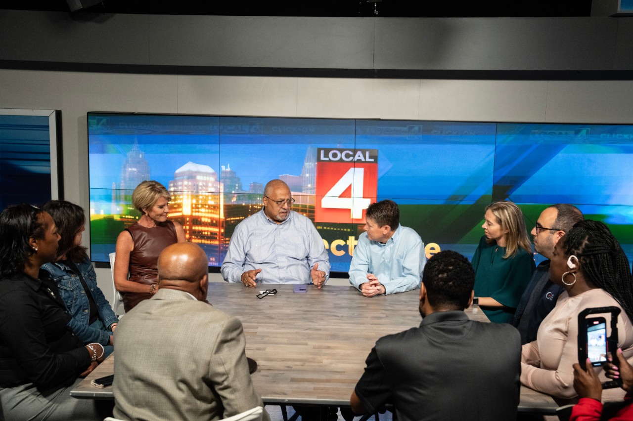 A group of people sitting around a table in a news studio.