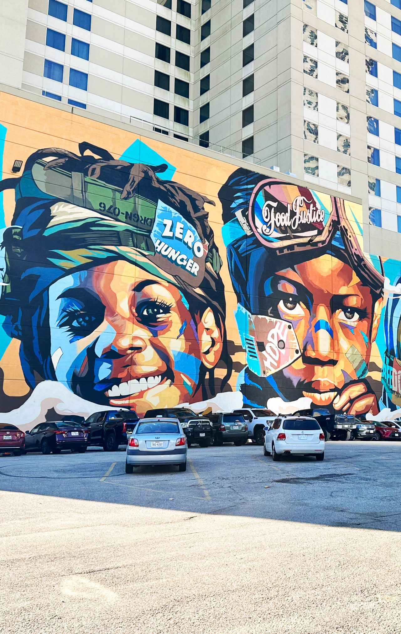 A mural on a city wall depicts a closeup image of four smiling Black children.