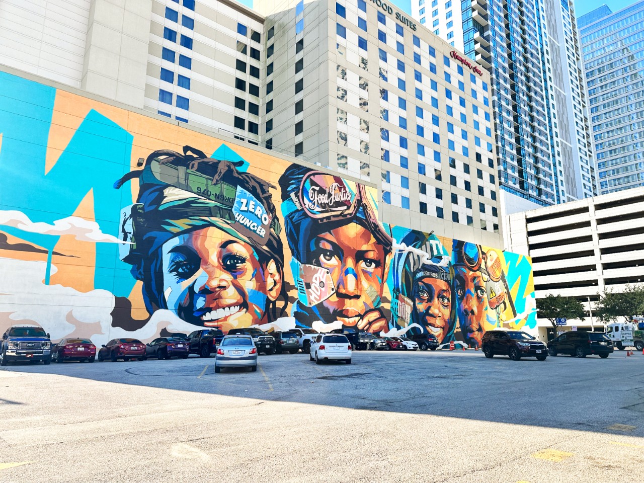 A mural in downtown Houston, TX shows closeup images of four smiling Black kids.