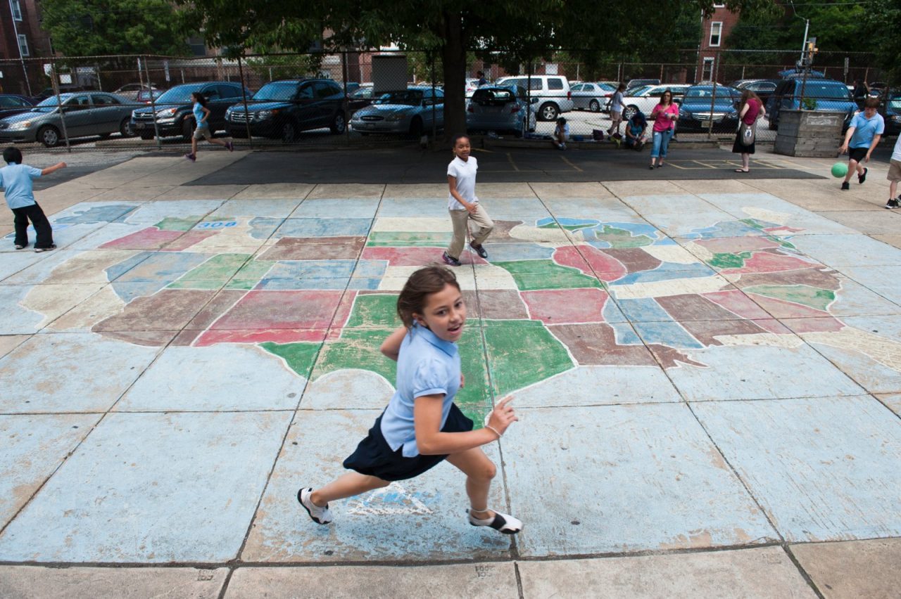 A girl running outside near a chalk drawing of the continental United States.