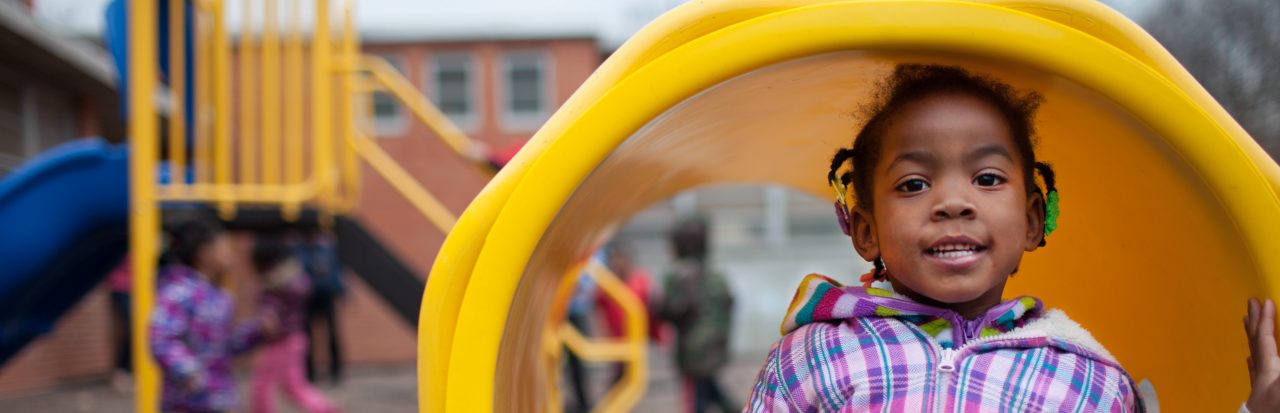 A young girl in playing in a tunnel at the playground.