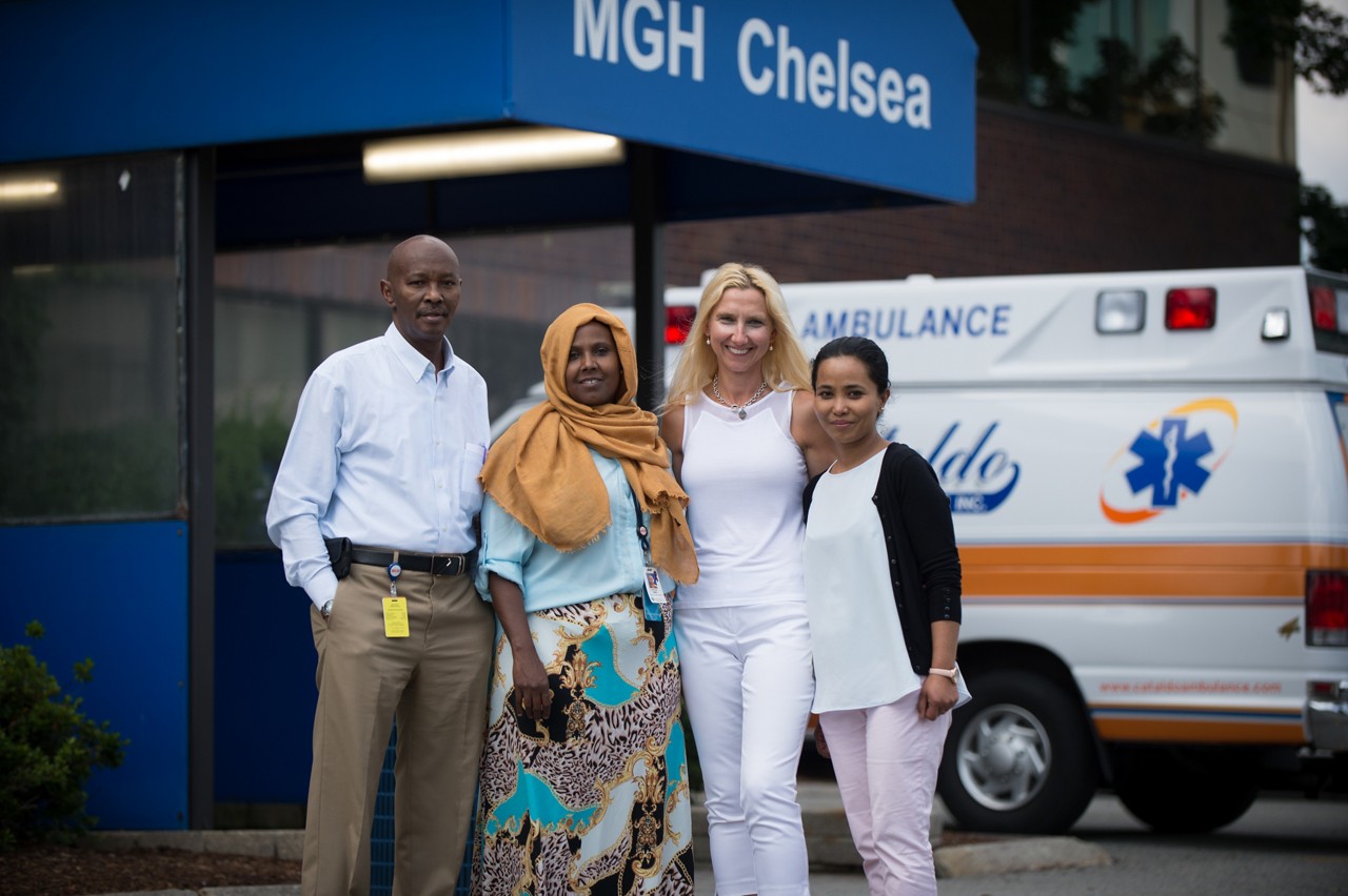 Four healthcare workers pose outside a hospital entrance. Four healthcare workers pose outside a hospital entrance.