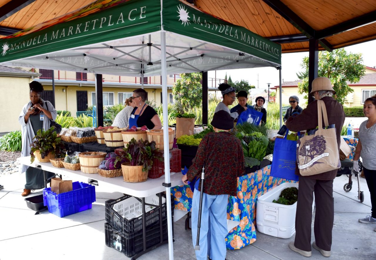 Residents shop at an outdoor marketplace booth