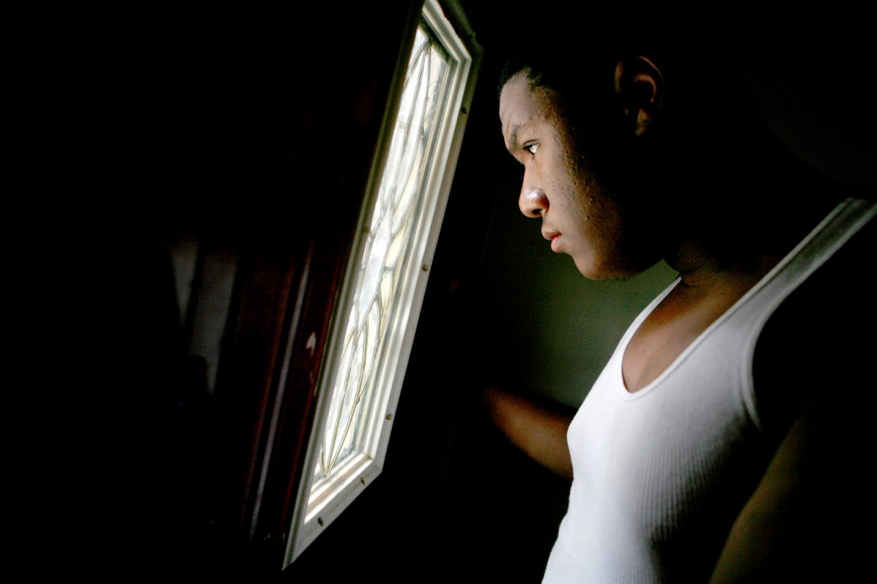 Commission for a Healthy America- Kenyon McGriff looks out of the door window in his home in West Philadelphia. Kenyon McGriff a High School student was overweight due to eating junk food and now belongs to Sayre High School running club, Students Run Philly Style.  West Philadelphia. PA.