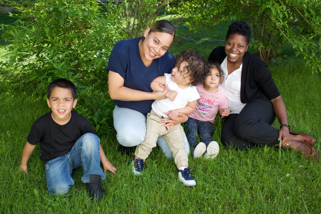Supportive Housing program case worker, Melissa Rowe (in white shirt) with her client Irma and three of Irma's four children: Joels, age 5, Delicia, age 3 and Julio, age 18 months. Melissa has provided support to Irma for over two years. 

Irma Rosales, age 24, left home at the age of nine after she and her brother suffered abuse at the hands of their step father. After several years in the care of foster homes and living homeless, Irma became pregnant at age 15. By the age of 23, Irma had lived through periods of homelessness and had become mother to four children with two different men, both of whom were abusive. Six months into her fourth pregnancy, Irma s partner threw her down the stairs and she went into premature labour. Medical staff told Irma that she would miscarry but her youngest son, Julio survived after spending the first six months of his life in hospital. The sustained involvement of medical professionals in Irma s life alerted the Supportive Housing program to her situation. Case worker Melissa Rowe began working with Irma, offering support, advice and providing the funds to purchase items for the care of baby Julio. Melissa made representations to the Department of Children and Families (DCF) to vouch for Irma s character and convince them that Irma should not be separated from her children. Melissa encouraged Irma to go back to school and complete her high school diploma. 

Supportive Housing  provided Irma a housing-voucher so that she could keep her children and live independently of her abusive partner. Irma now lives with her children who have rooms of their own and a back yard in which to play. Julio, now eighteen months, has significant health needs but the relative stability of Irma s life now means she can look to the future with a sense of optimism. She hopes to complete her associates degree in nursing and eventually earn an income that will allow her to live in accommodation without the need of a subsidy from Supportive Housing.