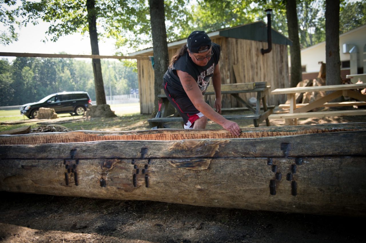John Redeye finishes a dugout canoe which he made in the traditional style from white pine. The inside was burned out with fire, causing the sap to push out of the sides and create a natural water resistance. The canoe will be displayed at the West Virginia Culture Center and State Museum.