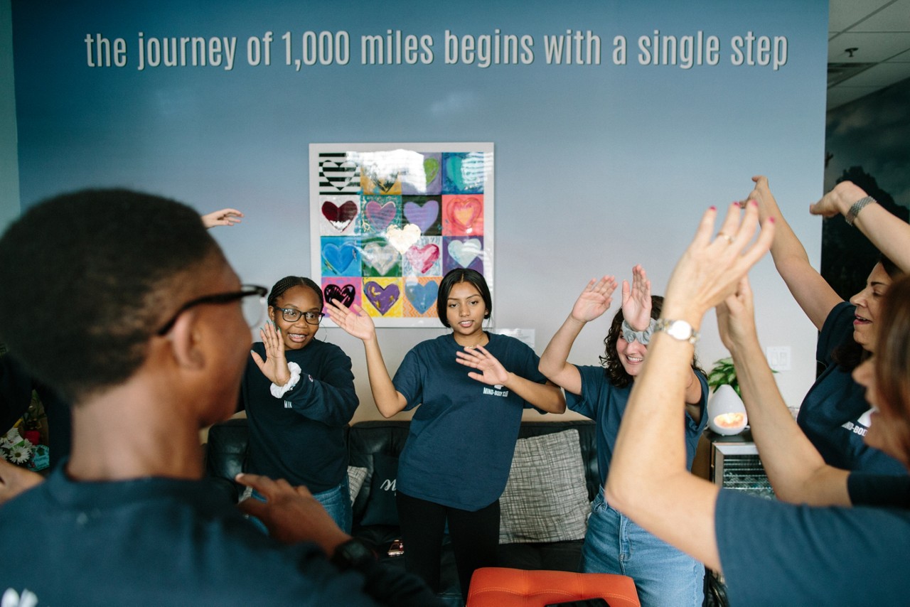 Parkland, FL - August 23, 2019 - Members of the "Mind Body Ambassadors" group from Marjory Stoneman Douglas High School meet at  Eagles' Haven. 
Next door to a health food store in a strip shopping center, a new drop-in wellness center presents an immediate aura of calm. A circle of teens practices deep breathing exercises. Other young people meet with staff in private rooms, decorated with murals of mountains and motivational sayings like, The best views come after the hardest climbs. This is Eagle’s Haven, and it is just across the highway in the Parkland neighborhood from Marjory Stoneman Douglas High School (MSD), where a lone shooter killed 17 and injured 17 on Feb. 14, 2018.
“I wondered, ‘How am I ever going to teach again?’ ” says Diane Wolk-Rogers, a history teacher at MSD. After going through training, she shared what she learned with students, staff and parents. The idea spread, and about 100 students now serve as Mind Body Ambassadors and teach calming techniques to others. The initiative has been so effective that CSC wants to introduce clubs across the school district.