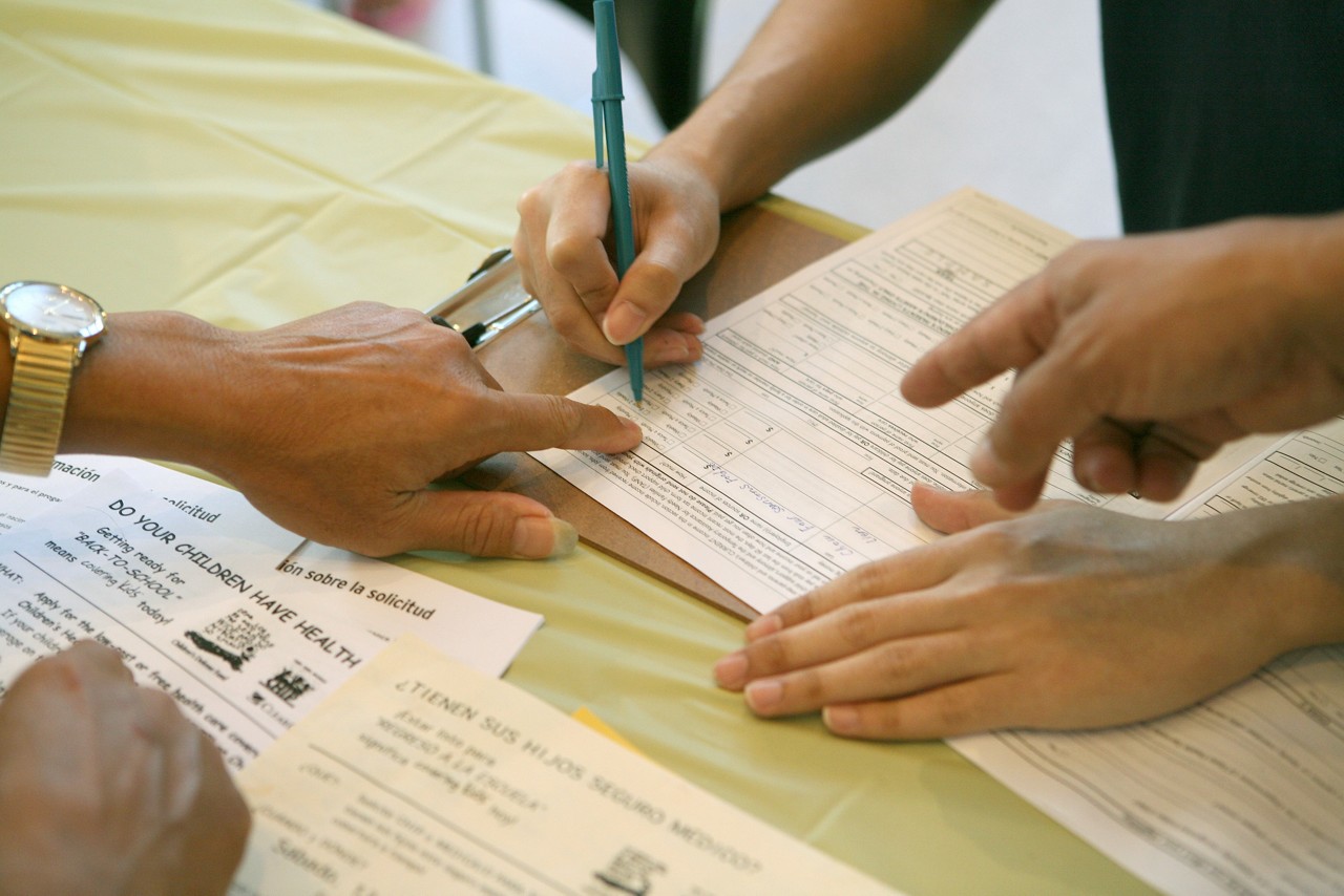 A man fills out an application for SCHIP (State Children's Health Insurance Program) at a Covering Kids &  Families enrollment event. Covering Kids & Families