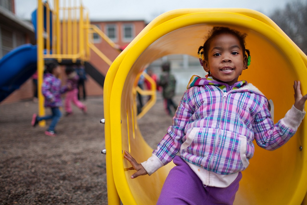 A young girl in playing in a tunnel at the playground.