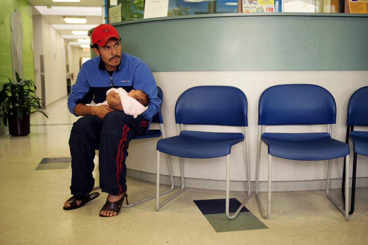 A man holds his newborn infant in a hospital waiting room.  MedVerse - Hablamos Juntos