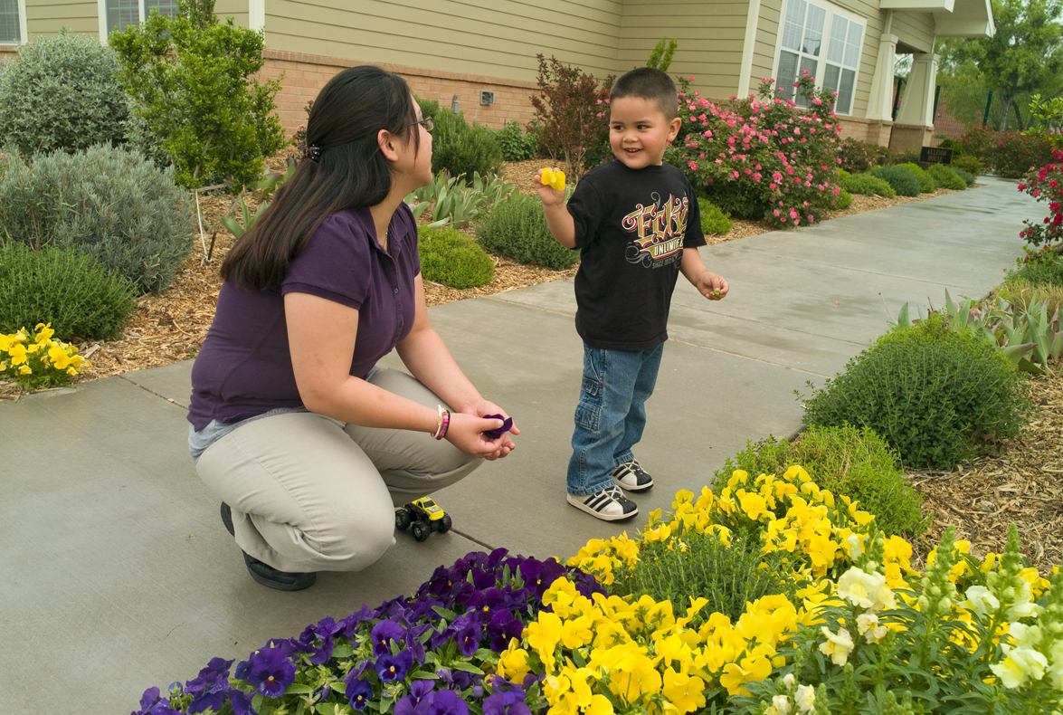 A woman with a young boy looking at flowers.