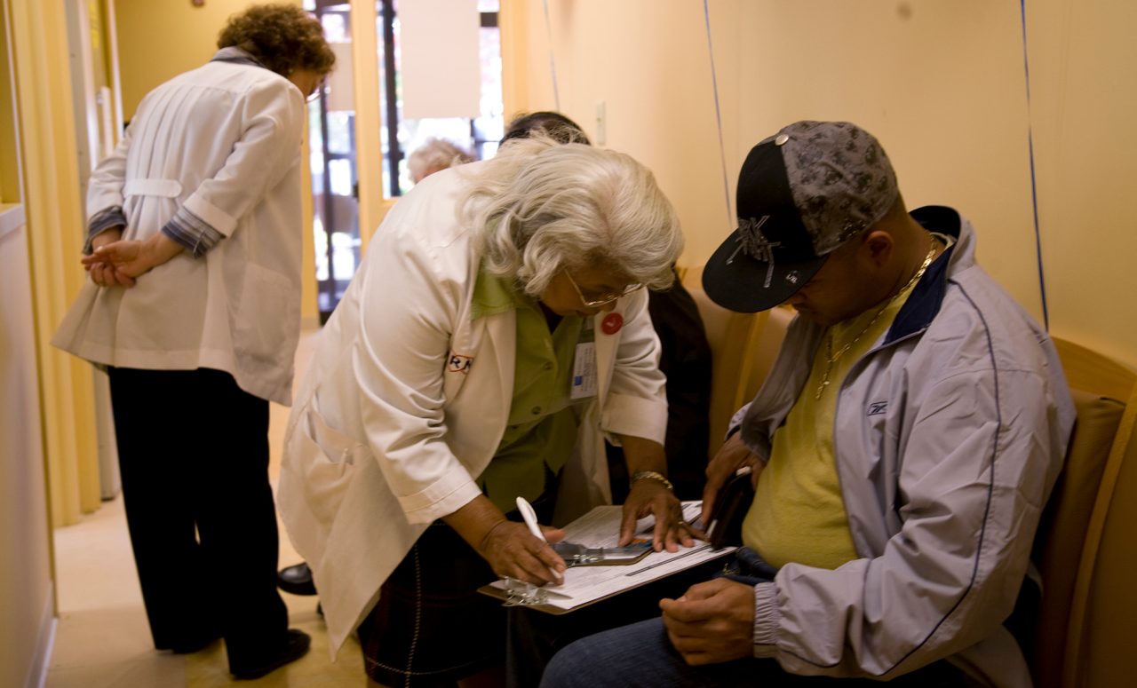 Nurses helping patients complete medical forms.