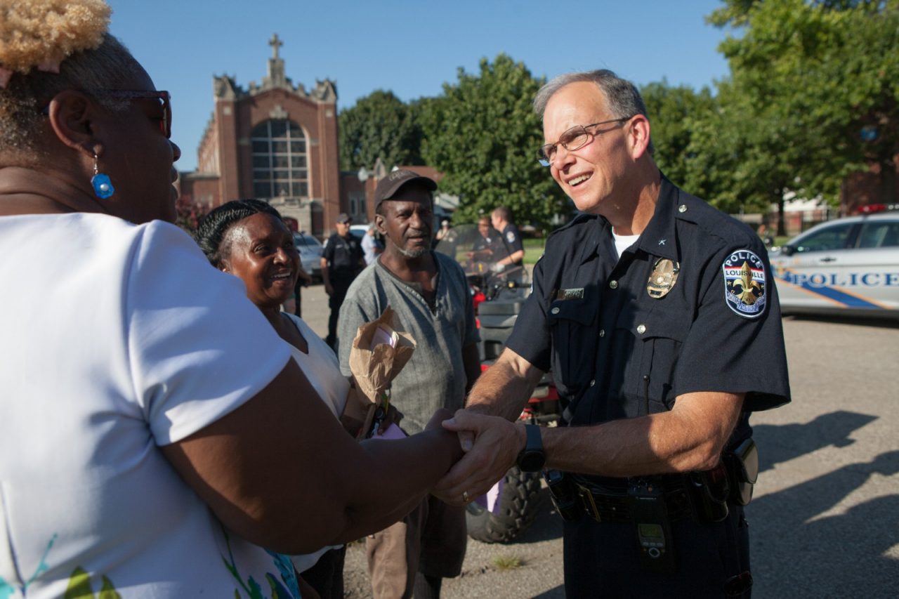 Policeman shaking hands with community members.