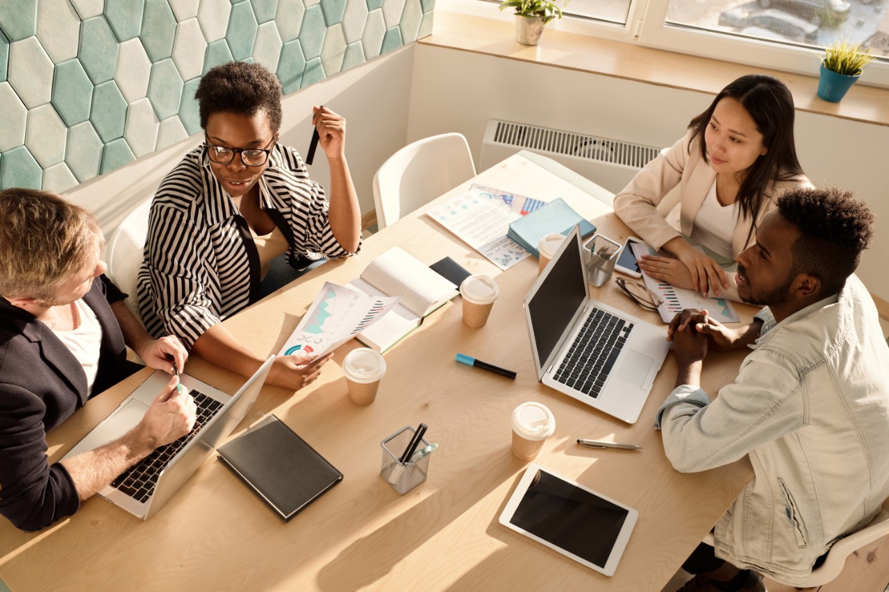 Four young, multi-racial professionals engaging in an office meeting.