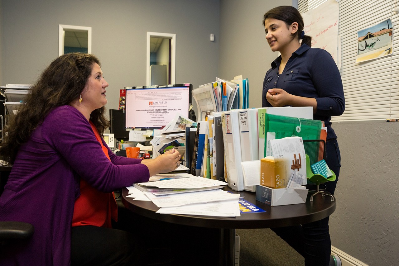 Leslay Choy, San Pablo Economic Development Corp. (EDC) General Manager, in her office with intern Roya Babayhosseini.
Residents of San Pablo understand all too well how economic hardship can worsen people’s health and spill over into problems in family life. “We know that the people with the greatest needs are at those outer edges,” says Leslay Choy.