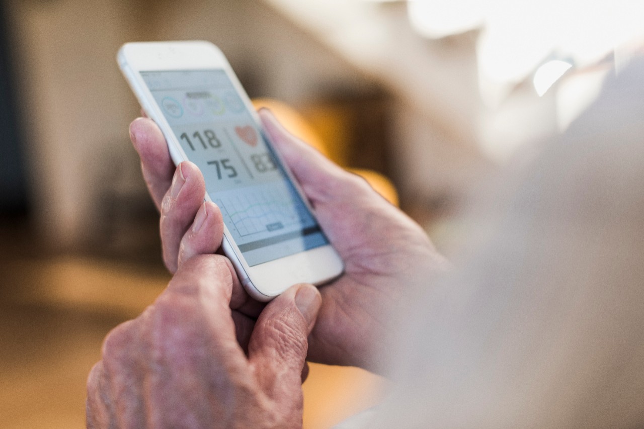 Male hands holding smartphone, checking blood pressure, heart rate with obscured other body parts.