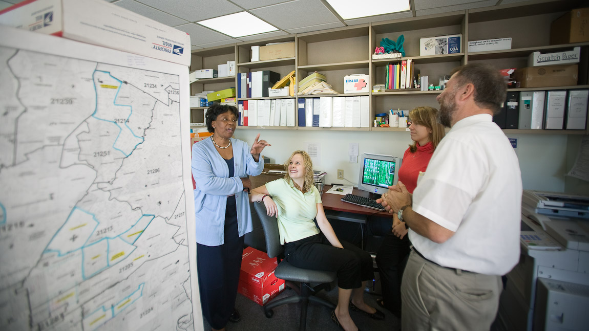 Coworkers talking in office. Vincent Demarco, director of Consumer Voices for Coverage, talks with co-workers.