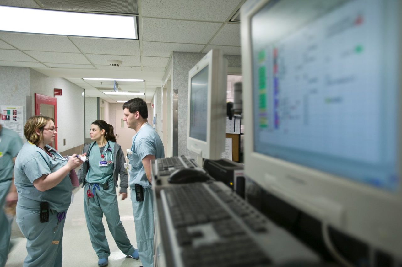 Health professionals standing near computer monitors.