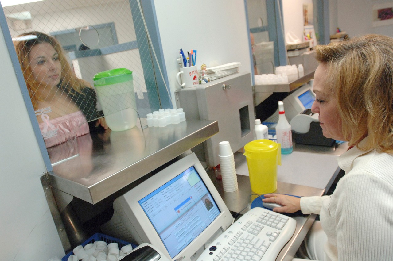 A patient talking with a nurse who is checking computer records.