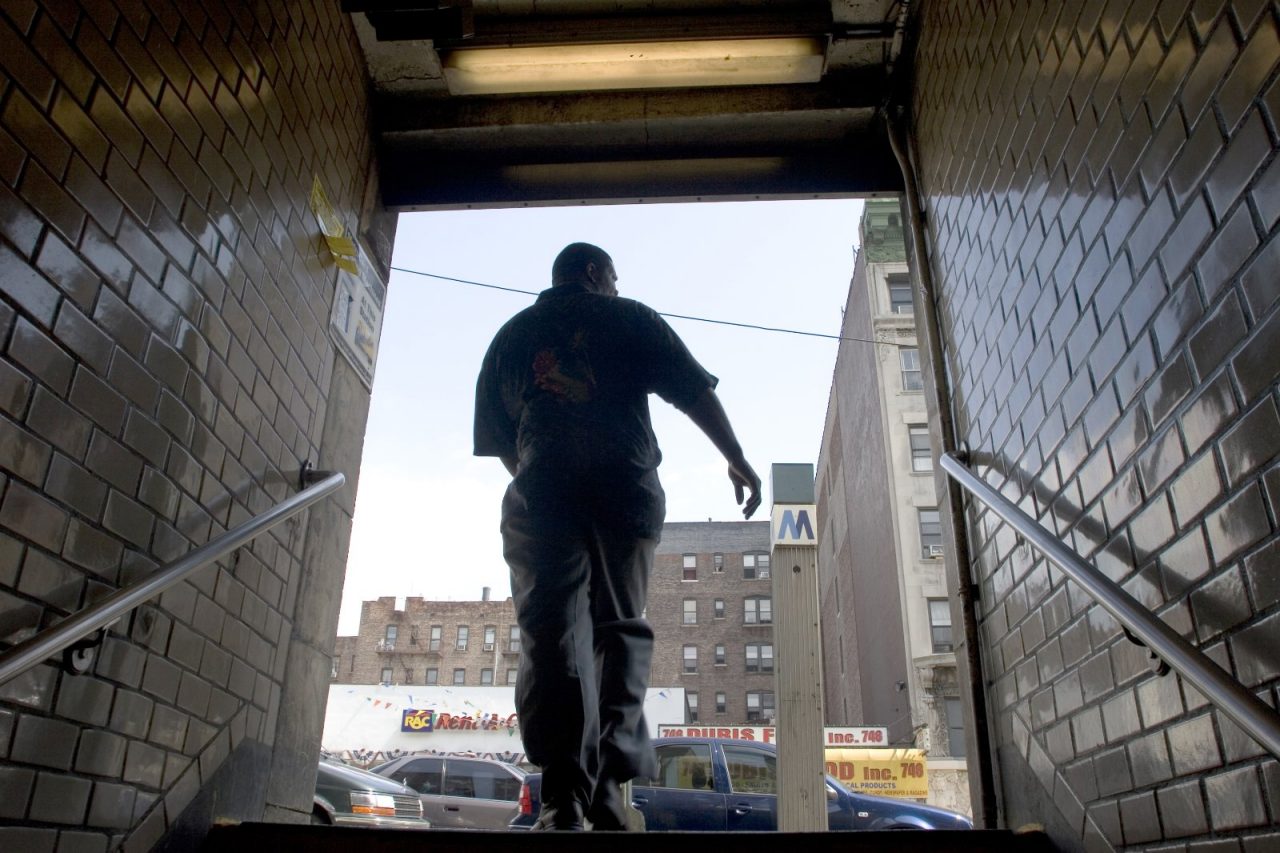 A man walking up the steps of a subway station.