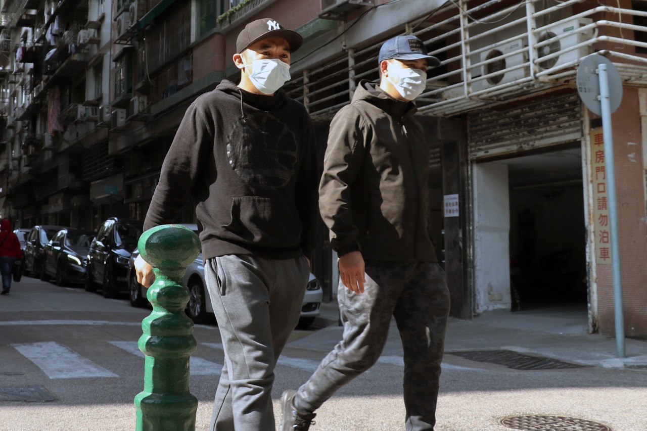 Men walking on street wearing protective masks.